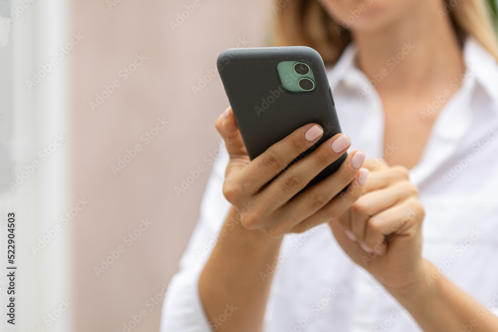 female hands hold a modern mobile phone on the street..education, modern app, shopping order, work online female hands hold a modern mobile phone on the street..education, modern app, shopping order, work online