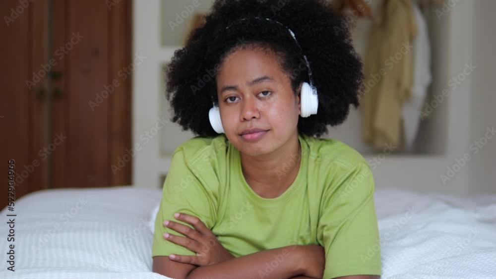 A portrait of an Afro Asian woman with dark skin who lies on the bed in