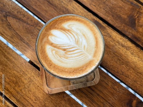 beautiful cup of cappuccino coffee with latte art in the wooden space background photo