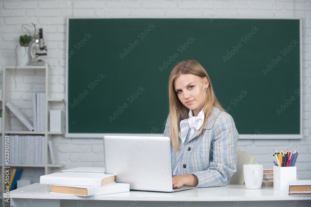 Young teacher. Female college student working on a laptop in classroom, preparing for an exam. Young teacher. Female college student working on a laptop in classroom, preparing for an exam.
