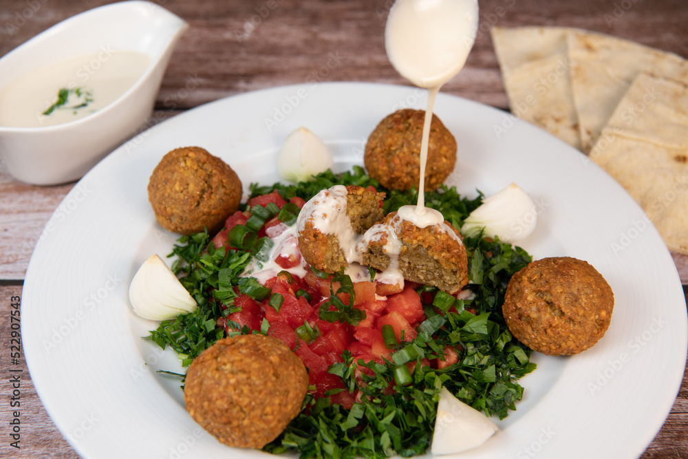 Vegetarian dish, falafel balls from spiced chickpeas with chopped parsley, fresh onions and tomato, tahini sauce, High quality photo Vegetarian dish, falafel balls from spiced chickpeas with chopped parsley, fresh onions and tomato, tahini sauce, High quality photo