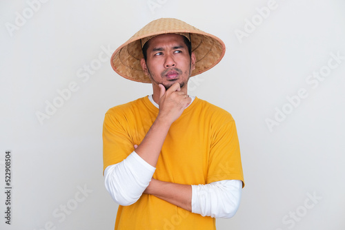 Young Indonesian farmer thinking about something with serious expression photo