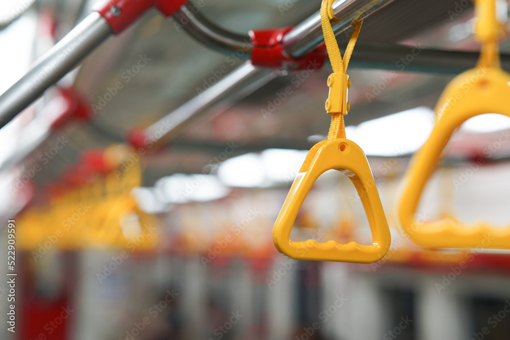 selective focus on yellow hanging handle grip on public transportation such as bus and train can be source of virus transmission and health issues.