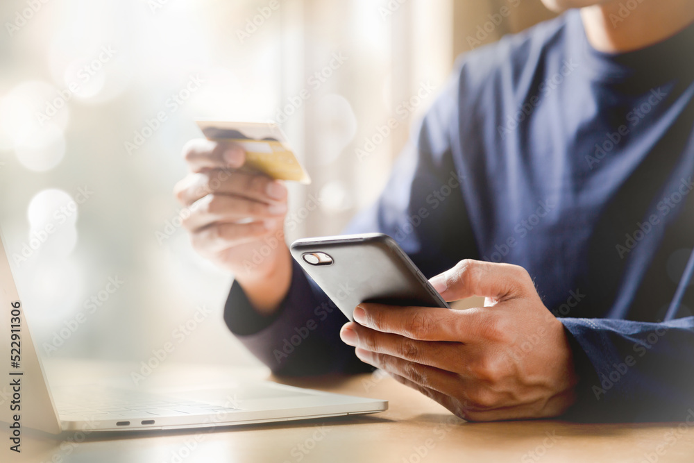 Man holding credit card and using smartphone at home online shopping ecommerce internet banking spend money work from home concept. Man holding credit card and using smartphone at home online shopping ecommerce internet banking spend money work from home concept.