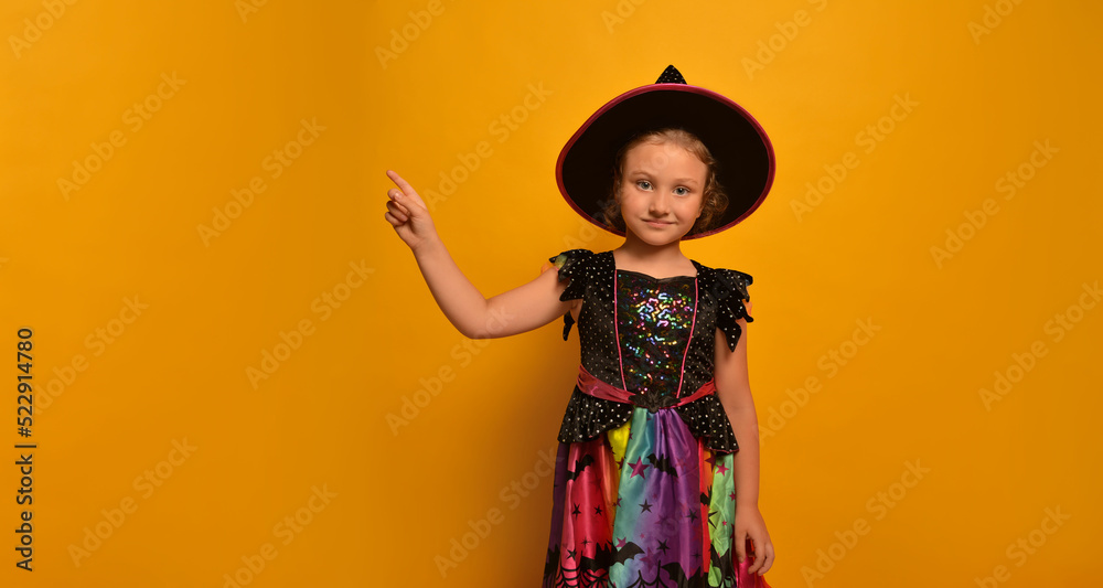 Little cute girl in witch costume pointing index finger up or holding finger up, showing free space for text or advert and looking at camera on a yellow background.
Happy Halloween and party concept. Little cute girl in witch costume pointing index finger up or holding finger up, showing free space for text or advert and looking at camera on a yellow background.
Happy Halloween and party concept.