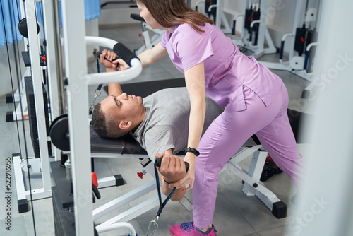 African American man doing rehabilitation exercise with physiotherapist photo