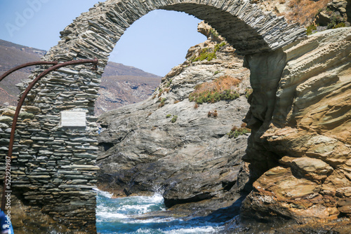 andros island stone arch in the sea of andros chora in greece photo
