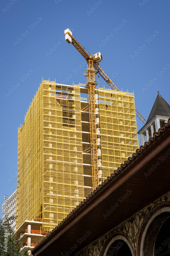 Fototapeta premium Albania, May 12, 2022 - Construction crane on top of unfinished building.