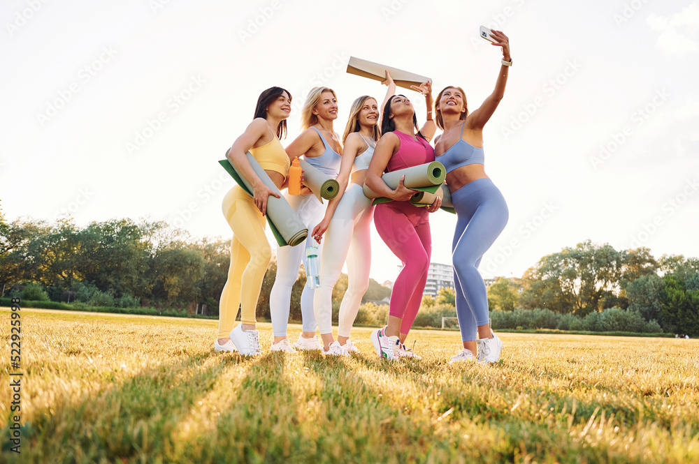 Fototapeta premium Taking a selfie. Group of women have fitness outdoors on the field together