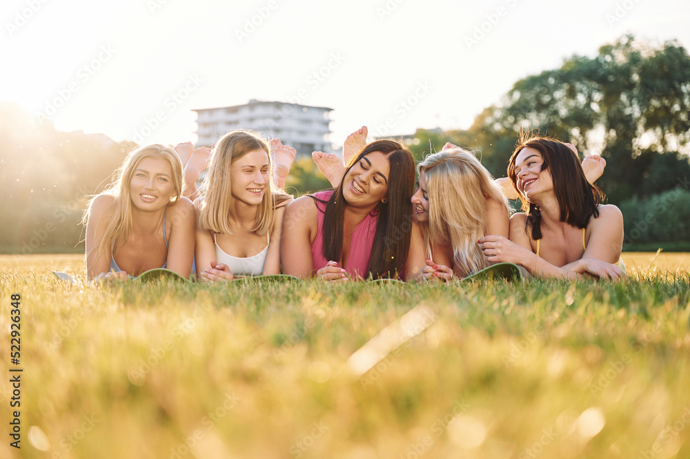 Laying down on the ground and smiling. Group of women have fitness outdoors on the field together Laying down on the ground and smiling. Group of women have fitness outdoors on the field together