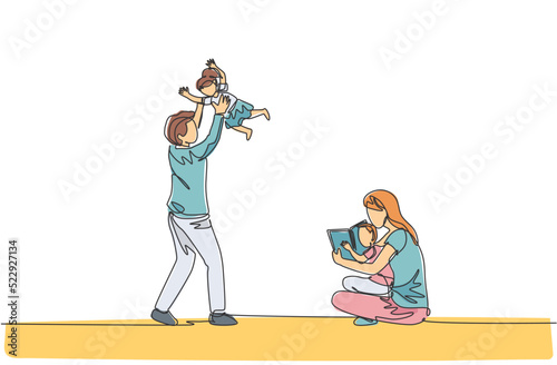 One single line drawing of young mother sitting on floor and reading book to son while father playing with daughter vector illustration. Happy family parenting concept. Continuous line draw design photo