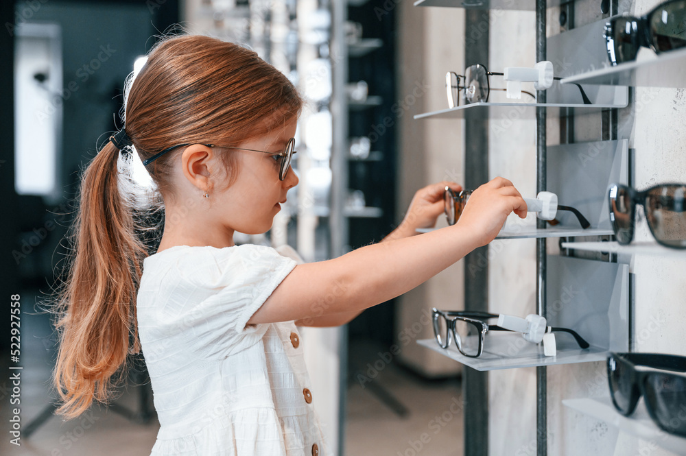 Many of the products. Little girl in the glasses store choosing eyewear