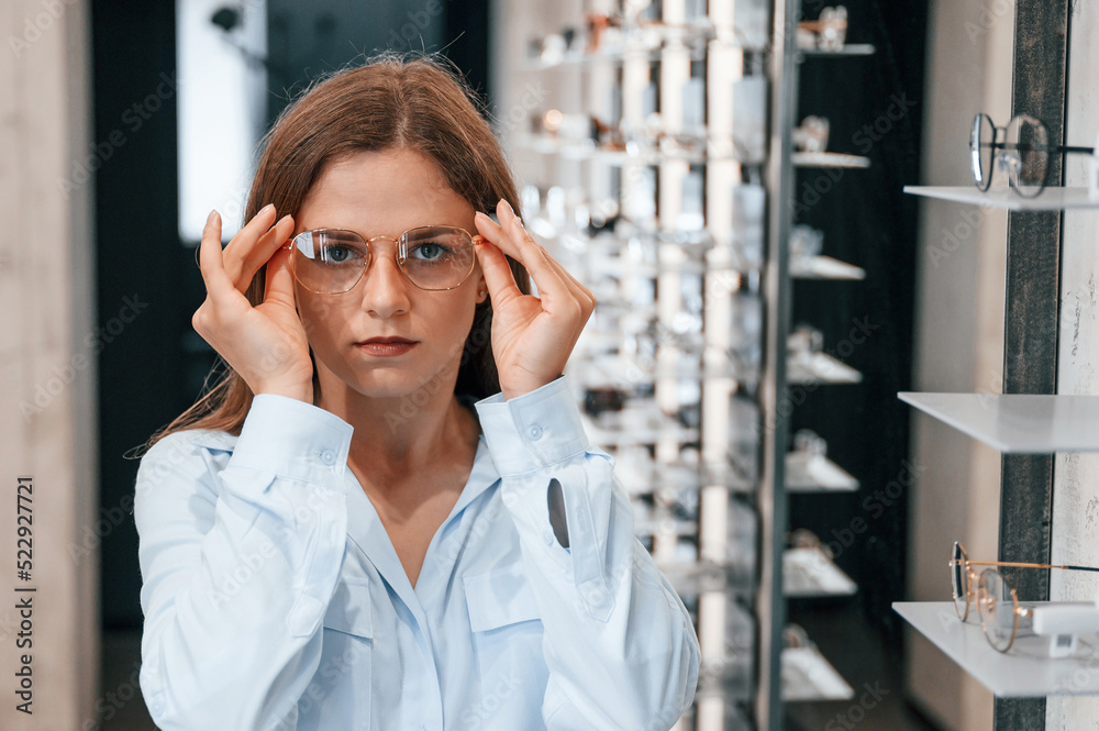 Portrait of woman that is with glasses in the store. Choosing right eyewear for correcting vision Portrait of woman that is with glasses in the store. Choosing right eyewear for correcting vision
