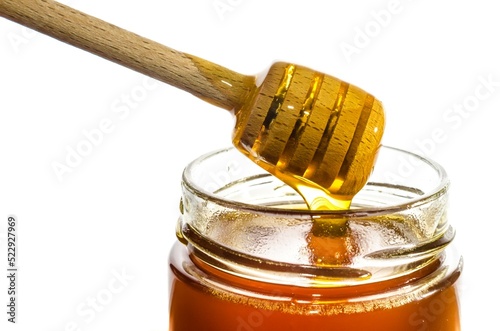 Honey in a glass jar with wooden honey dipper
