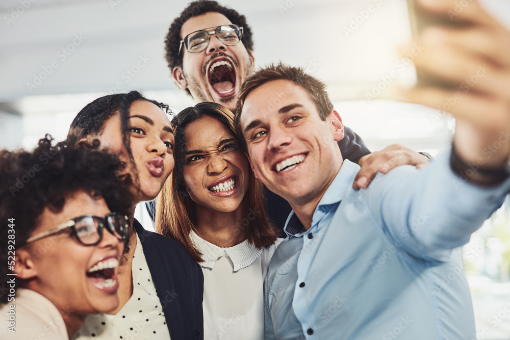 Teamwork, playful and selfie while a group of cheerful businesspeople making funny faces together for a social media post. Faces of a happy and fun team standing together in a creative office Teamwork, playful and selfie while a group of cheerful businesspeople making funny faces together for a social media post. Faces of a happy and fun team standing together in a creative office