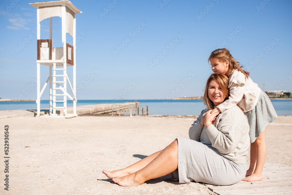 Happy family, mother and daughter have fun together in the sand beach against the sea or ocean . woman and kid spend time, happy people moments concept