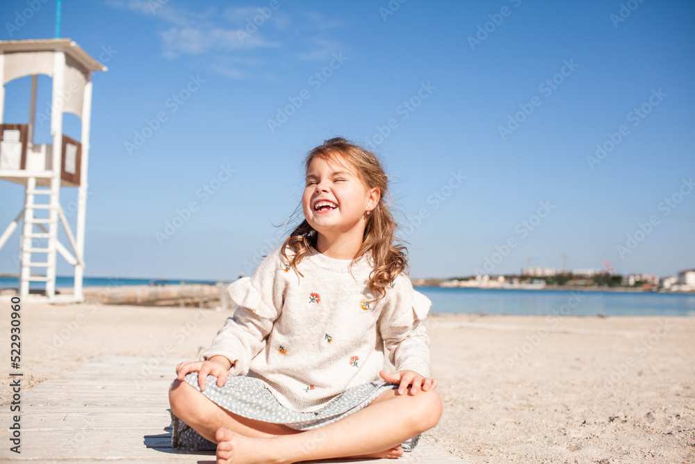 Happy female child have fun outdoor in the sand beach against the sea or ocean. Kid dress dress and sweater Happy female child have fun outdoor in the sand beach against the sea or ocean. Kid dress dress and sweater