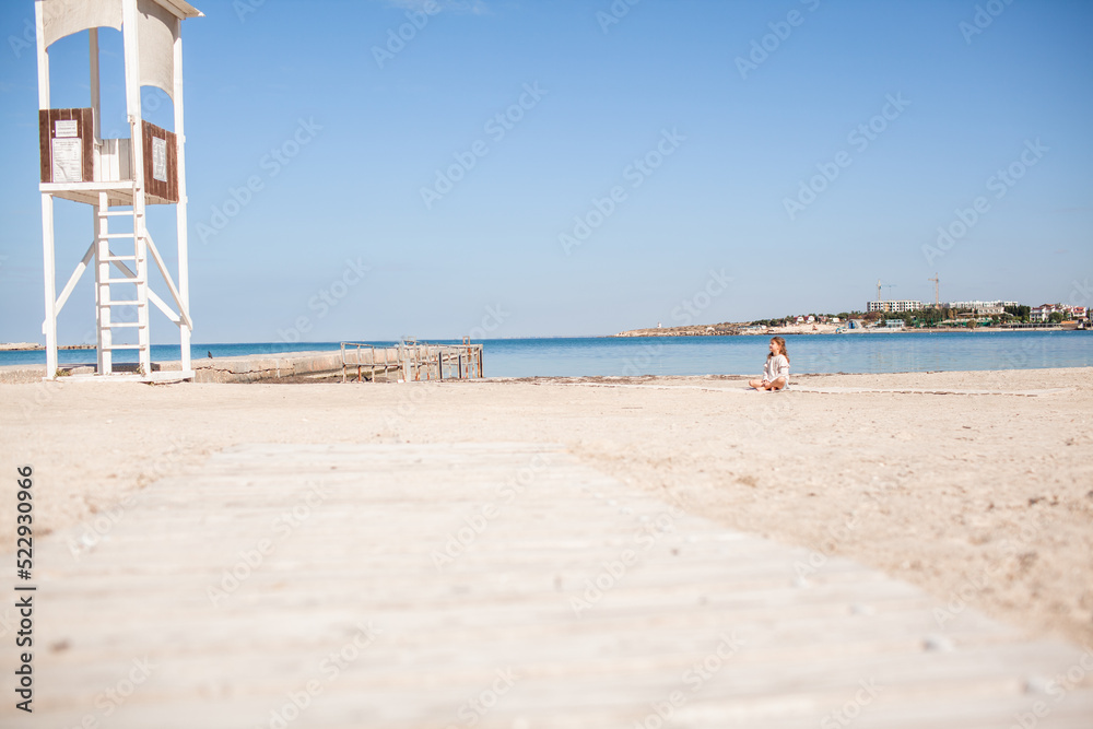 Happy female child have fun outdoor in the sand beach against the sea or ocean. Kid dress dress and sweater