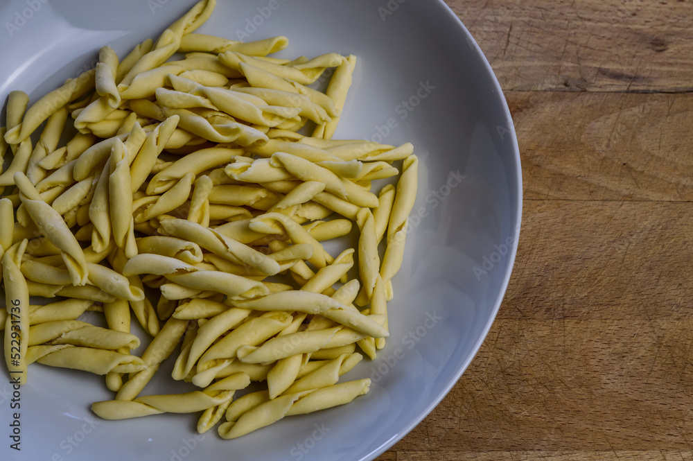 raw strozzapreti, specialties from northern Italy, fresh twisted pasta that cooks very quickly and is suitable for chunky sauces
