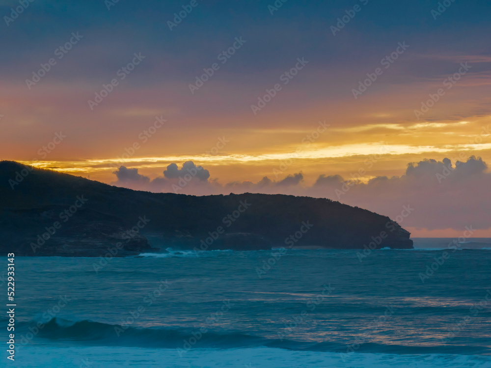 Cloud covered sunrise seascape and headland in soft pastel shades Cloud covered sunrise seascape and headland in soft pastel shades