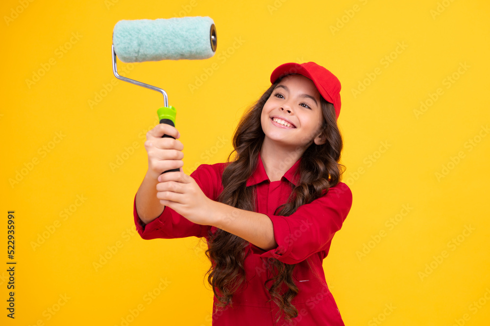 Positive and smiling builder in building uniform and cap. Painter painting with paint roller. Worker isolated on yellow background. Kids renovation concept. Positive and smiling builder in building uniform and cap. Painter painting with paint roller. Worker isolated on yellow background. Kids renovation concept.
