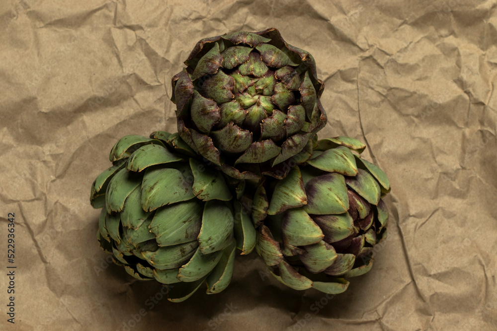 Obraz premium Big fresh green artichokes on paper background.