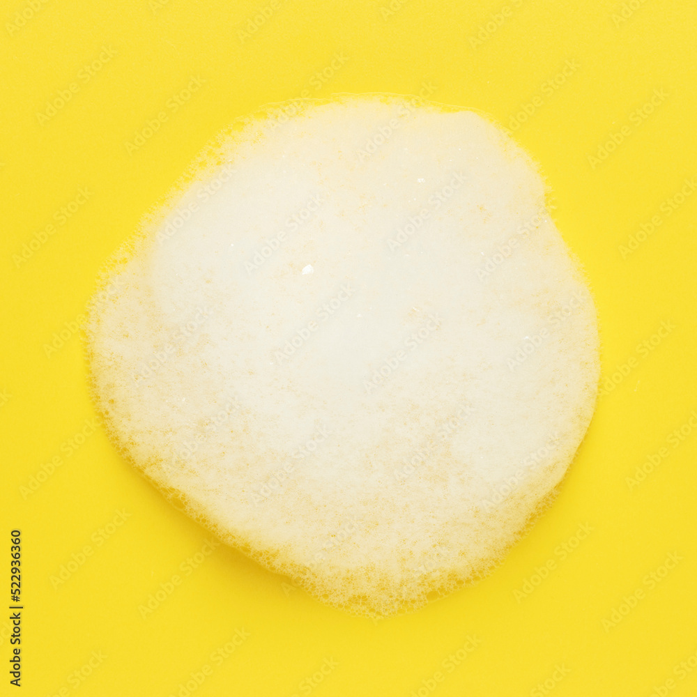 White fluffy foam on a yellow background. Top view. White fluffy foam on a yellow background. Top view.