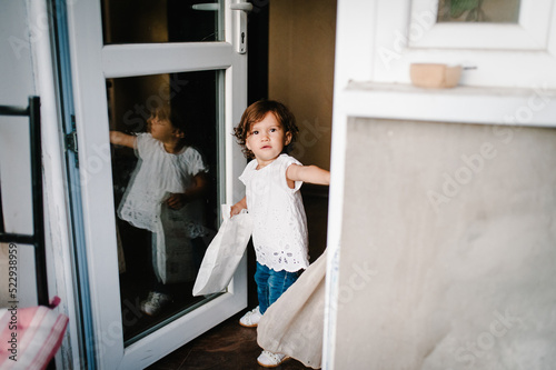 Little child girl opens locked door himself and go out onto the balcony to the street. Concept Safety of children. Girl of the house is alone. photo