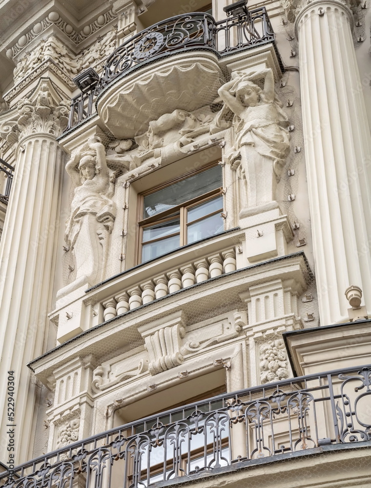 Fototapeta premium The facade of an old building decorated with caryatid sculptures, stucco molding and openwork balconies
