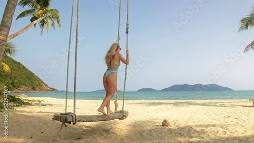 Pretty woman swinging on a swing on a tropical beach, on shores of the turquoise sea. Concept travel, walks, rest in sea, tropical resort coastline relaxation traveling tourism summer holidays