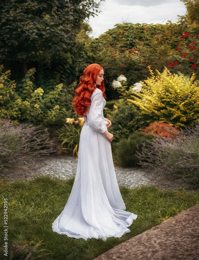 Fantasy red-haired woman walks in summer blooming garden. flowing red hair white historical style dress hem train. Girl sexy aristocrat back rear view leaves. Green nature trees Stock