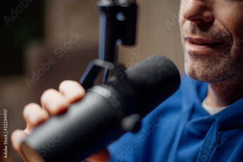 Close-up of mature man speaking in microphone during moderating podcast.