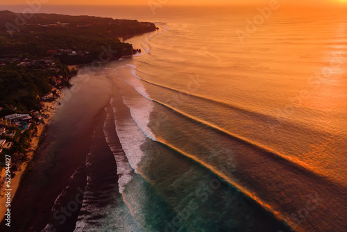 Fotografija Aerial view of coastline and surfing waves at warm sunset