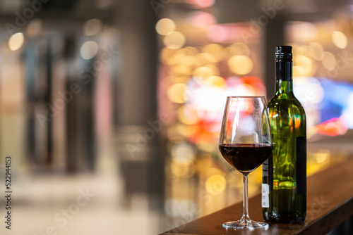 drinks and alcohol concept - close up of glass of red wine and bottle on bar counter at restaurant