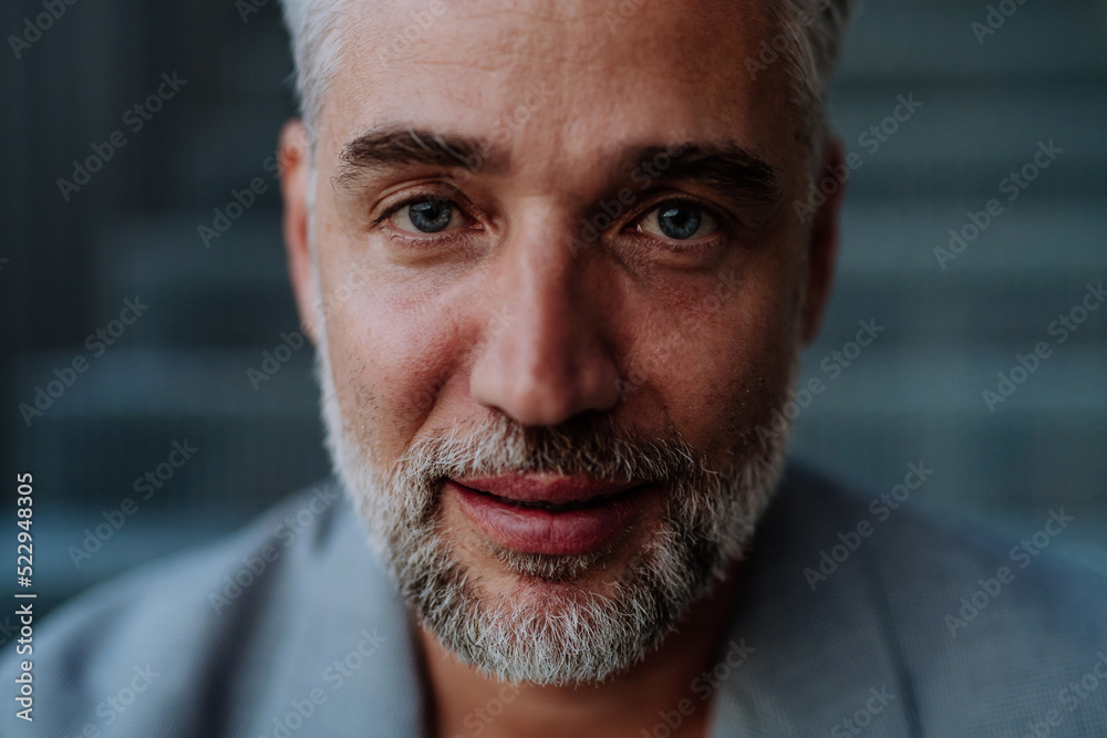 Fototapeta premium Close-up portrait of handsome businessman sitting out, looking at camera.