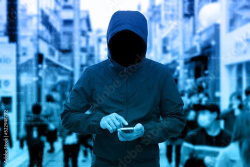 Anonymous man in a black hoodie using smartphone hacking. photo