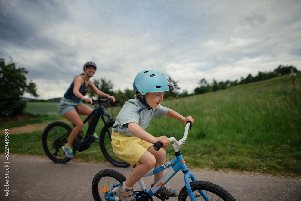 Young family with little child riding bicycles on road in village in summer. Young family with little child riding bicycles on road in village in summer.