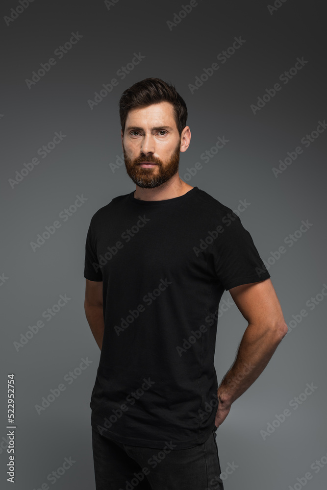 portrait of good-looking man in black t-shirt looking at camera isolated on grey. portrait of good-looking man in black t-shirt looking at camera isolated on grey.