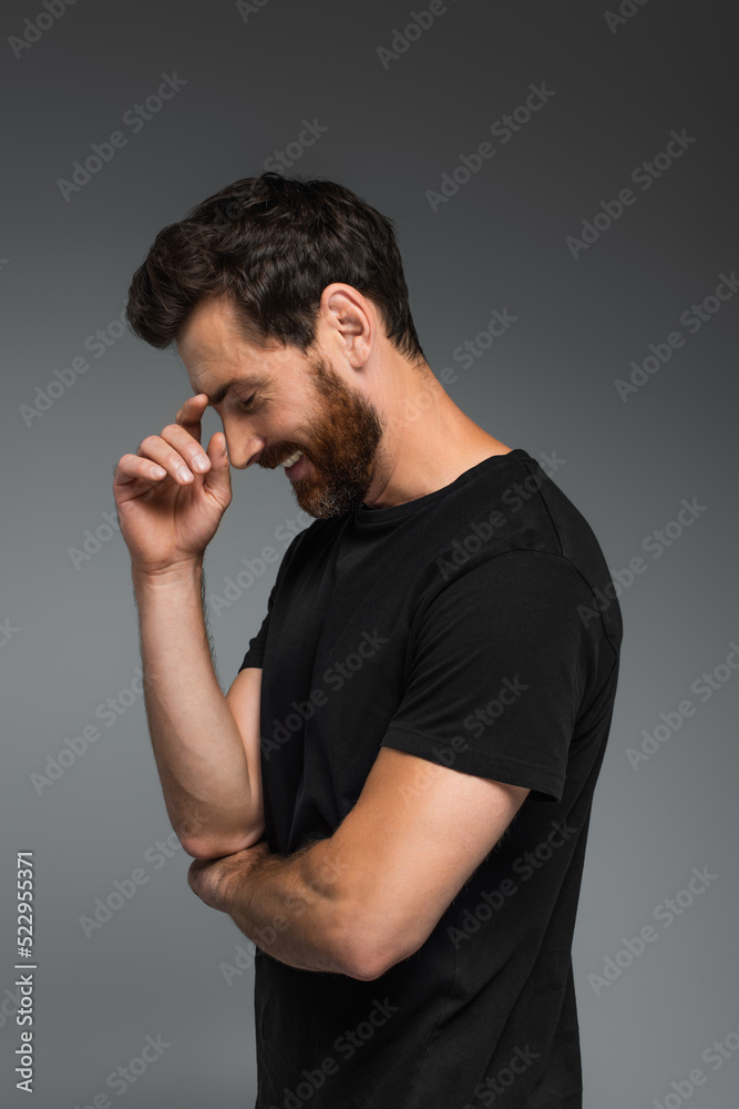 side view of cheerful man in black t-shirt smiling isolated on grey. side view of cheerful man in black t-shirt smiling isolated on grey.