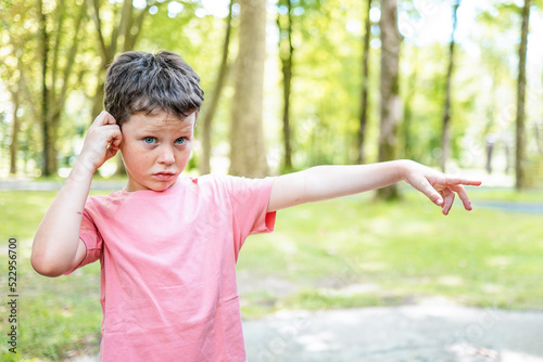 Upset boy pointing away in park