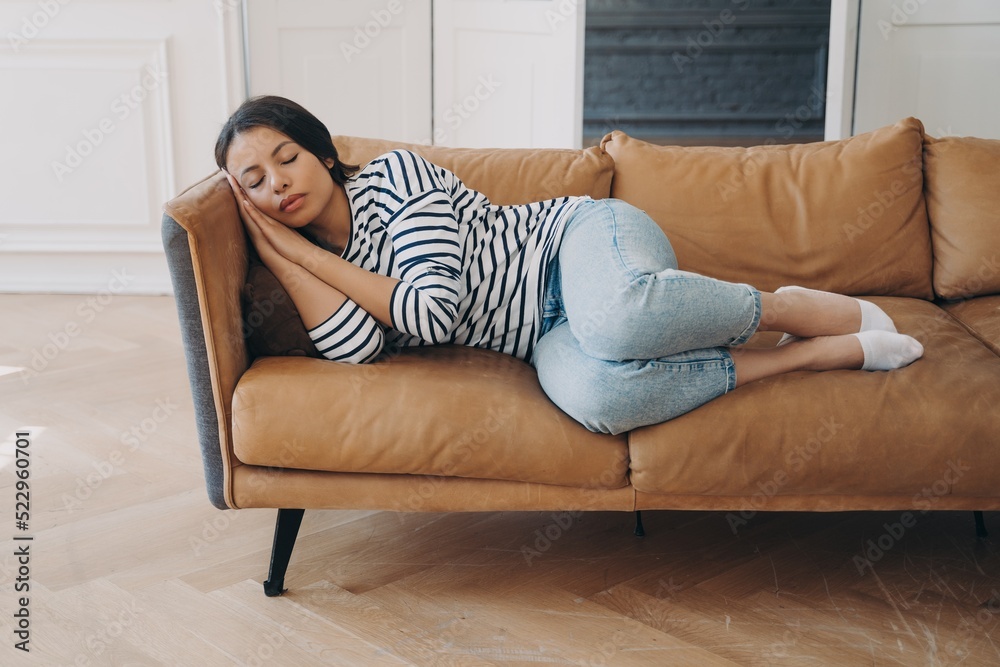 Tired female sleeping lying on comfortable cozy couch, napping, enjoy recreation after hard work day Tired female sleeping lying on comfortable cozy couch, napping, enjoy recreation after hard work day