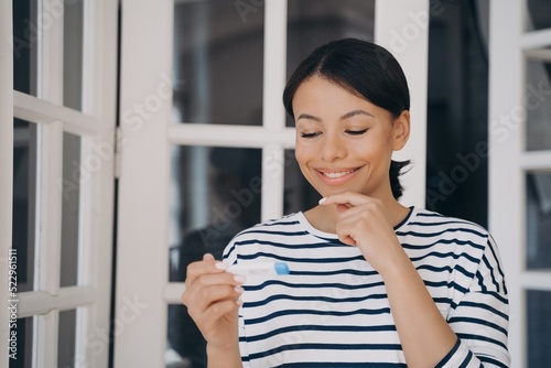 Female holding thermometer, smiling, pleased with normal body temperature. Wellness, convalescence