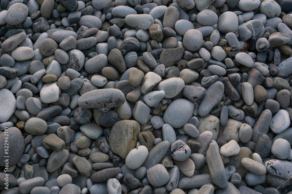 Sea stones background with small pebbles or stone in garden or in the seaside or on a beach. A close up view of rounded smooth polished pebble stones