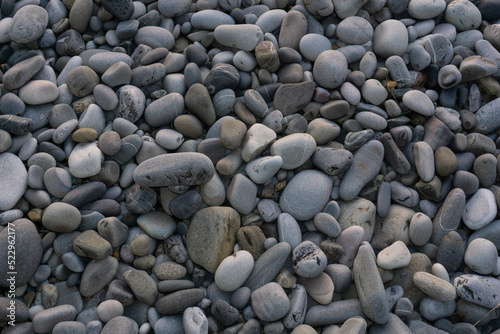 Sea stones background with small pebbles or stone in garden or in the seaside or on a beach. A close up view of rounded smooth polished pebble stones