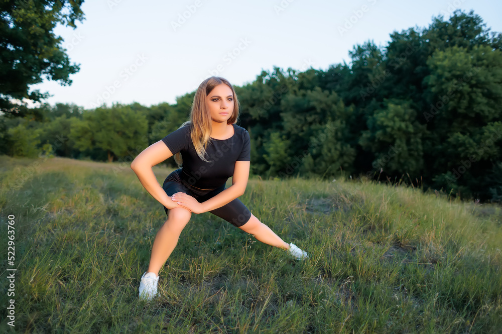 athletic blonde goes in for sports in the park performs exercises to stretch the muscles of the legs athletic blonde goes in for sports in the park performs exercises to stretch the muscles of the legs