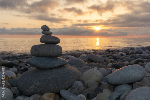 Stack of zen stones on the beach at sunset  beautiful seascape. Made of stone tower as rest balance vacation concept.