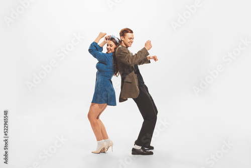 Portrait of young beautiful couple, stylish man and woman dancing at the retro party isolated over white studio background