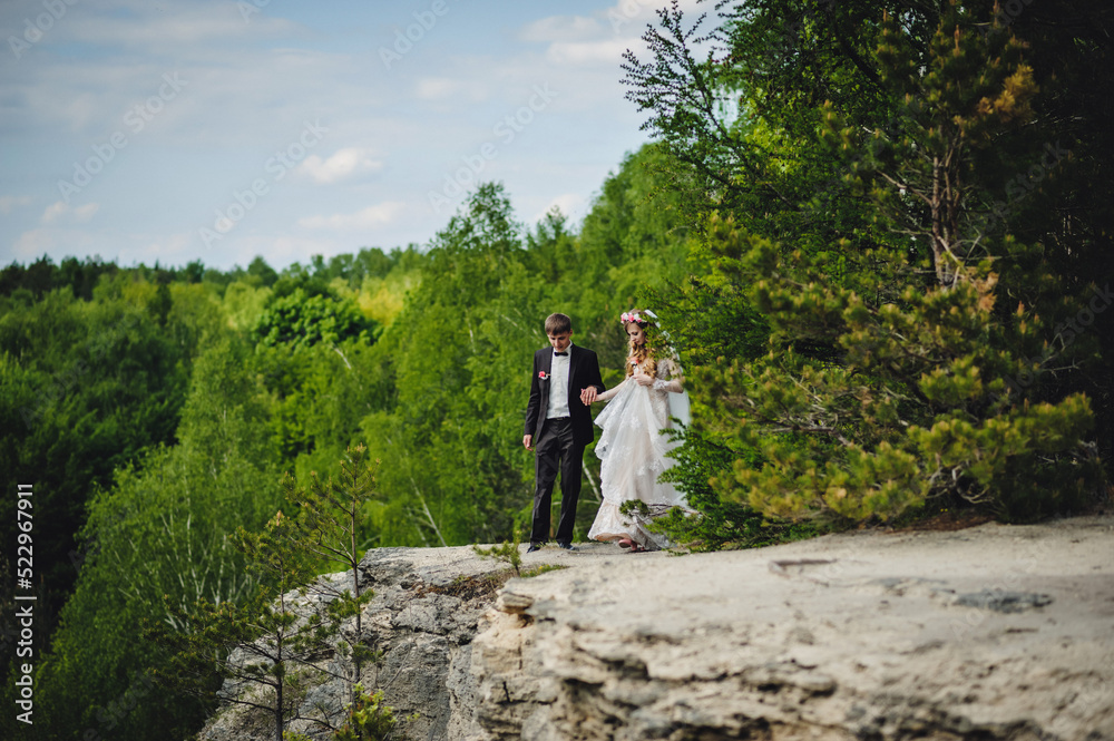 The bride and groom on the nature. Portrait of an attractive couple in country. Wedding ceremony near stony, rocky wall. Newlyweds getting married outdoors.