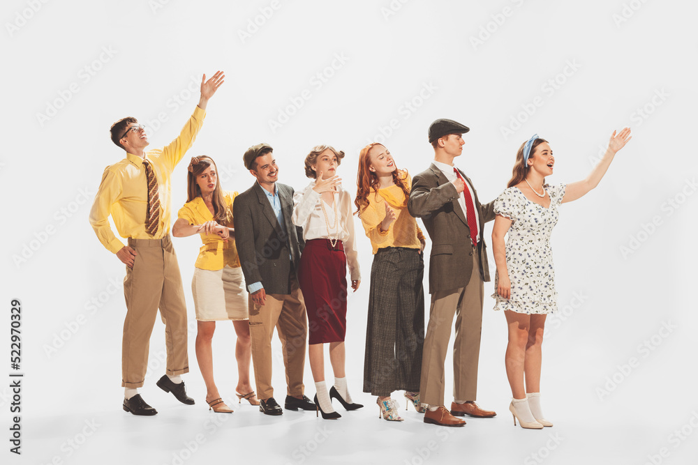Obraz premium Group of young stylish people standing in a line, talking, expressing ideas isolated over white studio background