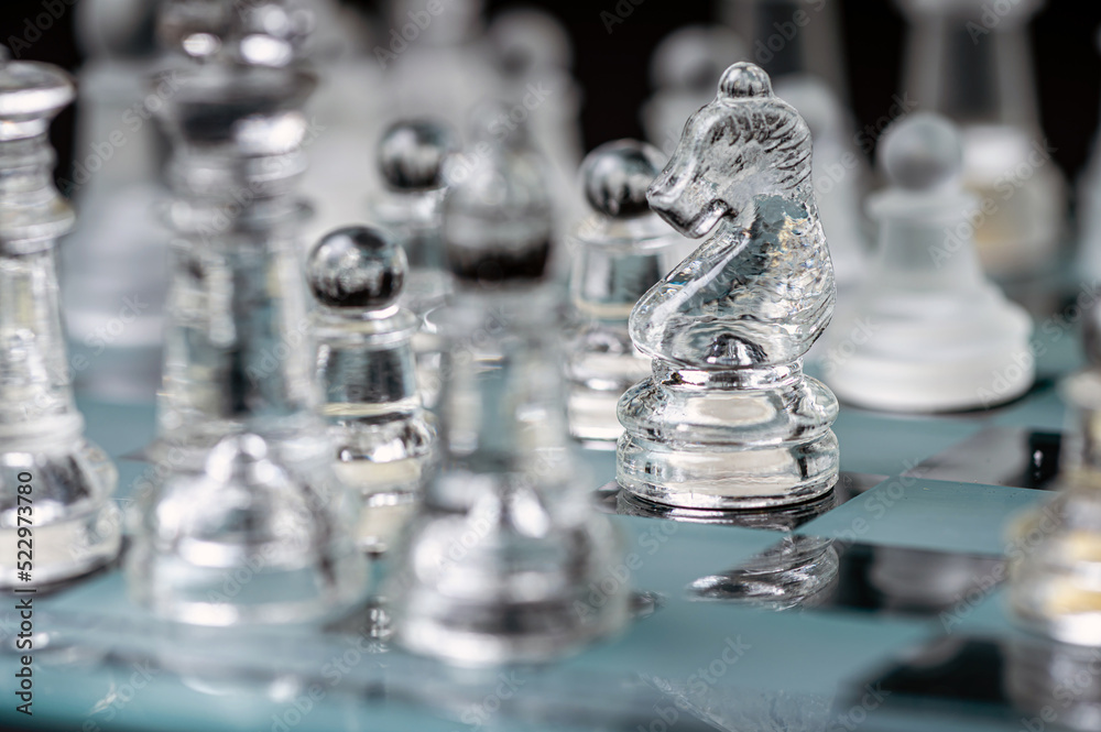 transparent glass chess on dark background, selective focus on horse piece, close-up transparent glass chess on dark background, selective focus on horse piece, close-up